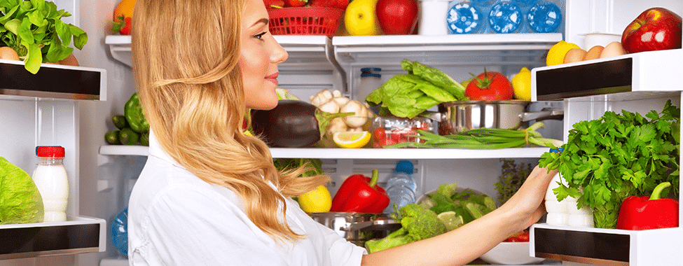 Woman Filling Fridge with Healthy Food for Post-Holiday Detox