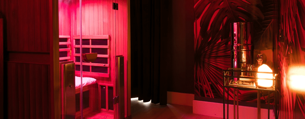 A relaxing room bathed in red light with a view inside of a sauna