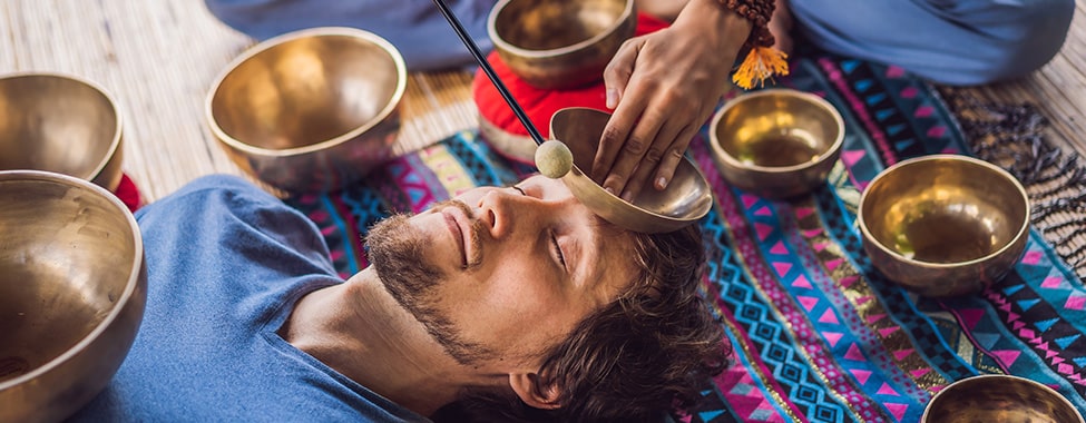 Man receiving sound therapy with singing bowls