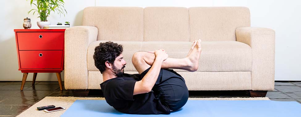 Man Doing Wind-Removing Pose for Hot Yoga at Home