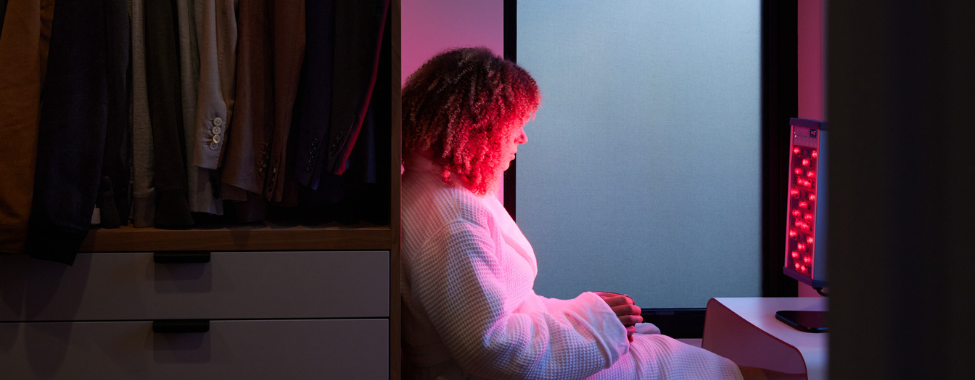 Woman in Small Wellness Room Using Personal Red Light Device