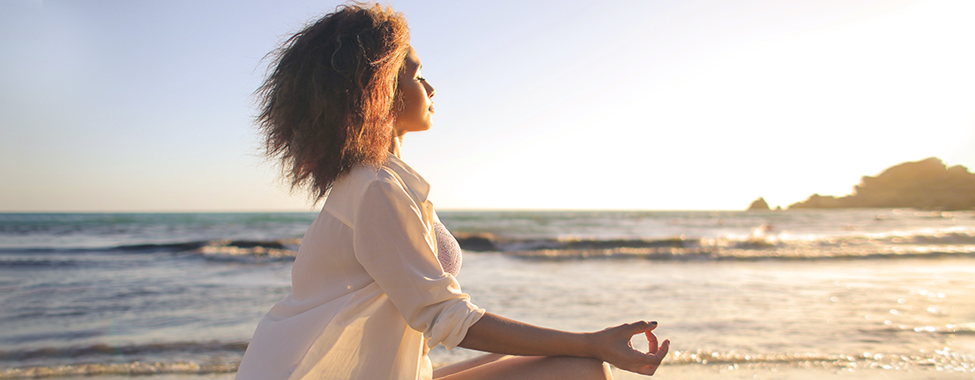 Woman Meditating on Beach for Restorative Travel
