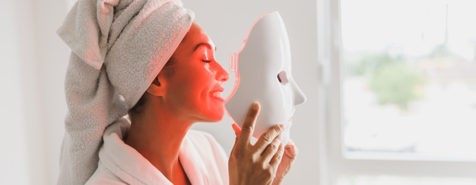 Woman Putting on LED Red Light Mask