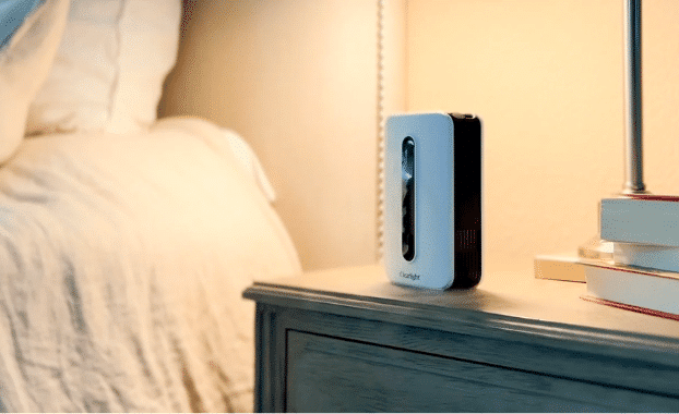 The Clearlight AROMA ONE diffuser on a nightstand beside a bed, enhancing indoor air quality with aromatherapy